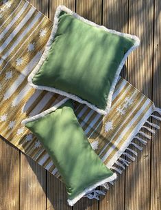 two green and white pillows sitting on top of a wooden floor next to each other