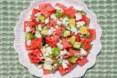 watermelon, cucumber and feta salad on a paper plate over a green tablecloth