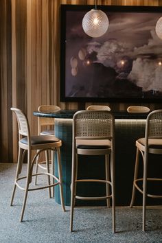 a bar with four stools and a television mounted on the wall