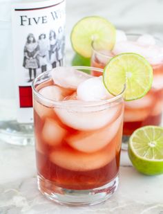 two glasses filled with ice and some limes