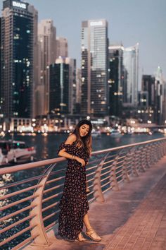 a woman standing on the edge of a bridge in front of a cityscape