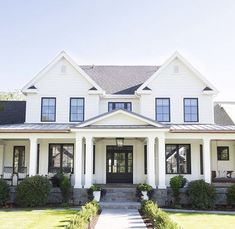 a large white house with lots of windows on the front and side of it's porch