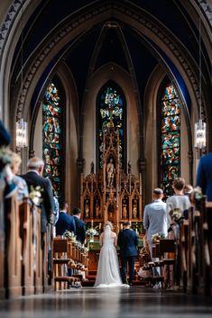 a bride and groom walking down the aisle at their wedding ceremony in front of stained glass windows