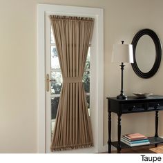 a room with a table, mirror and door that has the curtains pulled back to let in light