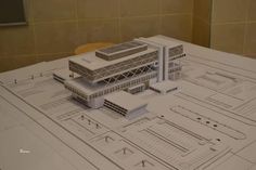 a model of a large building on top of a white table in front of a tiled wall