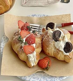 two croissants with strawberries and cream on them