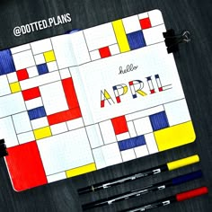 an open notebook with the word april written on it next to some markers and pens