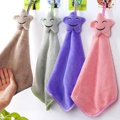 three towels hanging on the wall with faces drawn on them, one is pink and one is blue