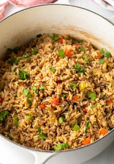 a pot filled with rice and veggies on top of a white tablecloth