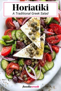 a white plate topped with sliced tomatoes, cucumbers and olives next to a salad