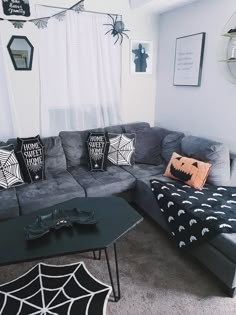 a living room decorated for halloween with spider webs on the walls and black couches