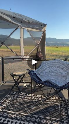 a table and chairs on a patio with a tent in the background