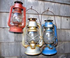 three different colored lanterns hanging from a wall