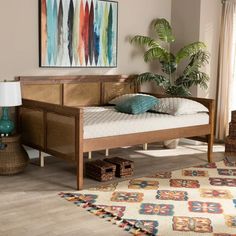 a bed sitting on top of a wooden floor next to a rug and table lamp