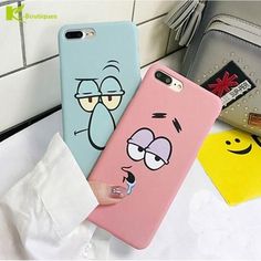 two cartoon phone cases sitting on top of a counter next to a purse and wallet