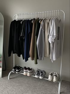 a rack with shoes and t - shirts hanging from it's hooks in front of a mirror