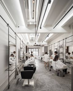 a group of people getting haircuts in a room with mirrors on the walls