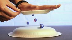 a person is throwing marbles into a bowl on top of a white plate,