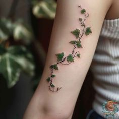 a woman's arm with green ivy leaves on the left side of her arm