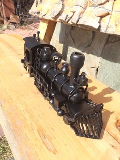 a toy train sitting on top of a wooden table next to a stone wall and fence