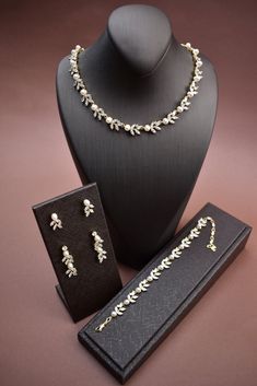 a necklace and earring set on a mannequin with a black box next to it