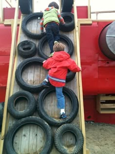 two children playing on an obstacle made out of old tire rims and wood planks