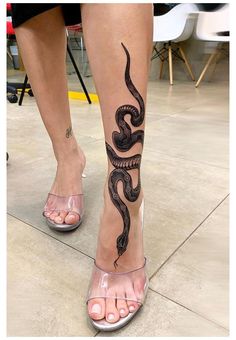 a woman's legs with a snake tattoo on them