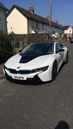 a white and black sports car parked on the side of a road next to houses