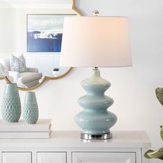 a blue vase sitting on top of a white table next to a lamp and mirror