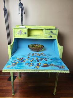 an old desk has been painted bright green and blue with colorful designs on the top