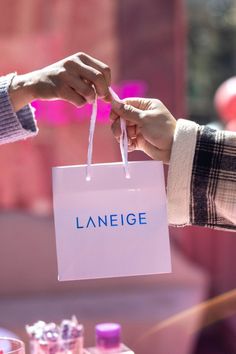 person handing another person a Laneige shopping bag Laneige Packaging, Pop Up Shop Invitation, Kylie Pop Up Shop, Pop Up Store Invitation, Neon Pop Up Store, Lip Sleeping Mask, Balloon Installation, Double Decker Bus