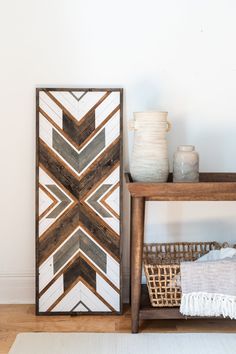 a white vase sitting on top of a table next to a wooden frame with an arrow pattern