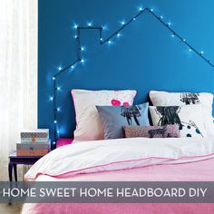 a bedroom with blue walls and lights on the headboard is decorated in pink and white