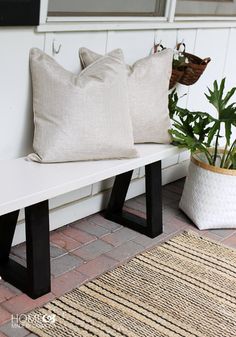 two pillows on a bench next to a potted plant