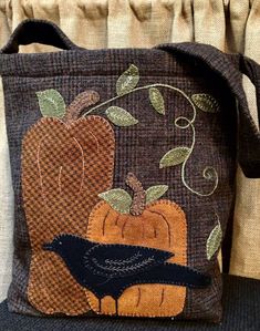 a brown bag with a black bird and pumpkins on the front is sitting on a chair