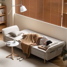 a person laying on a couch with a blanket over their head, in a living room