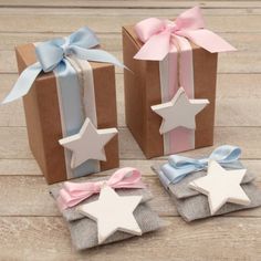 three small gift boxes with bows and stars on them, one has a pink ribbon