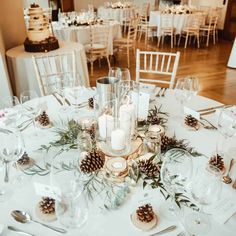 the table is set with pine cones, candles and place settings for an elegant winter wedding