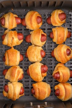 hotdogs wrapped in crescented bread are being cooked on an air fryer