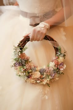 a woman in a wedding dress holding a flower wreath