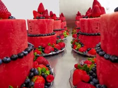 several red cakes with berries and blueberries on them are sitting in front of each other