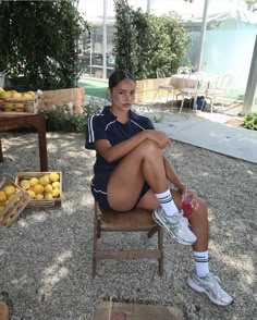 a woman sitting in a chair with lemons on the ground and other fruit behind her