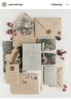 the wedding stationery is laid out on top of each other with flowers and envelopes