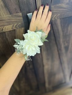 a woman's hand holding onto a door handle with flowers on it and greenery