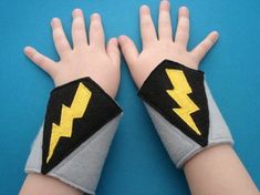 two children's hands with wrist wraps decorated like lightning bolt gloves on blue background