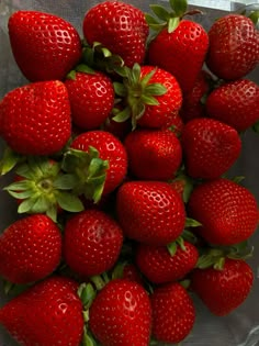 a bunch of red strawberries sitting on top of each other in a glass bowl