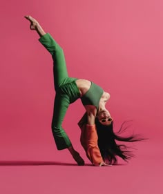 a woman doing a handstand in front of a pink background