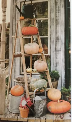 pumpkins and gourds are stacked up on a step ladder in front of a house