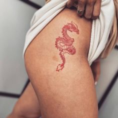 a woman with a dragon tattoo on her thigh is holding onto the side of her leg