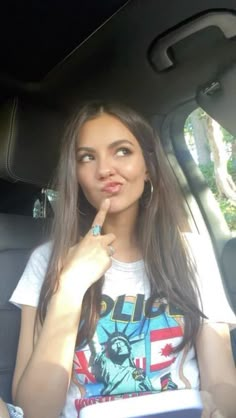 a woman sitting in the back seat of a car with her finger on her lips